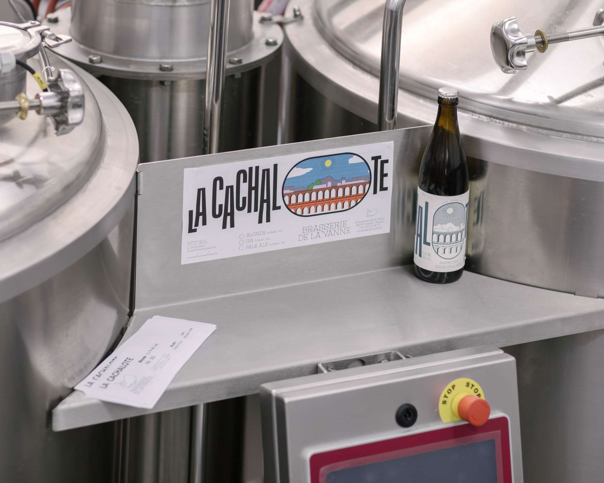Photo d'une bouteille de bière devant des cuves en inox de brasseur