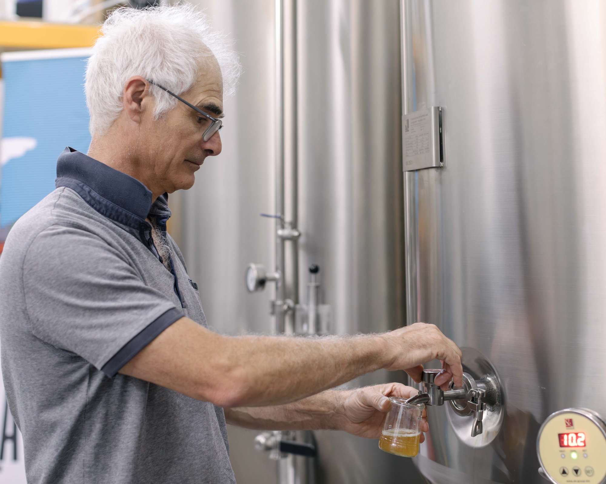 Photo du brasseur ouvrant une vanne d'une cuve en Inox.